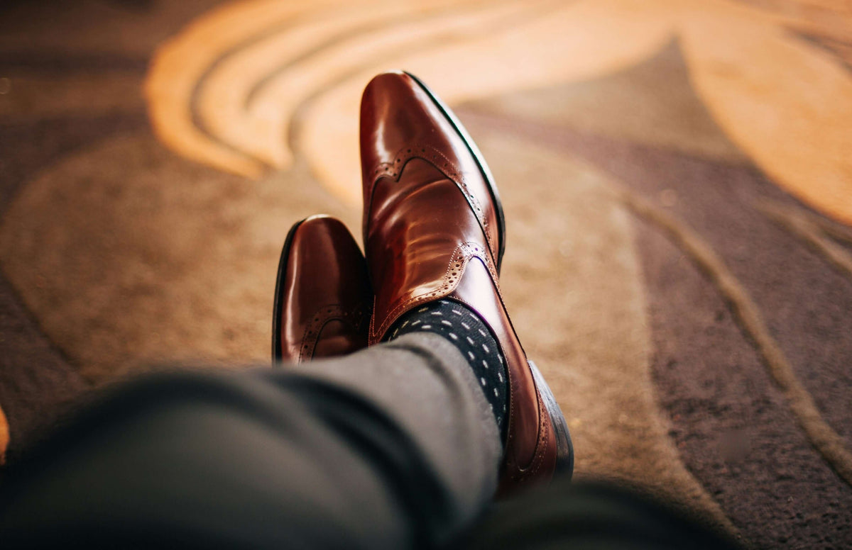 Home page. A man wearing spotty socks and shiny brown shoes.